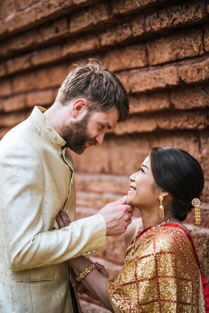 La sposa asiatica e lo sposo caucasico hanno tempo romantico con il vestito della Tailandia