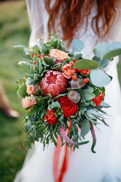 La sposa dai capelli rossi tiene il mazzo perfetto di nozze fatto di rosso