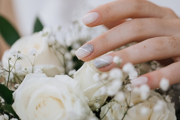 La sposa dimostra la sua manicure sopra il mazzo di nozze
