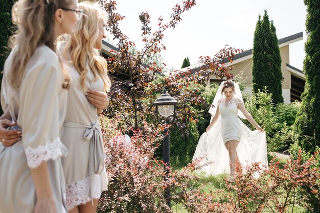 La sposa e le sue amiche camminano nel giardino soleggiato