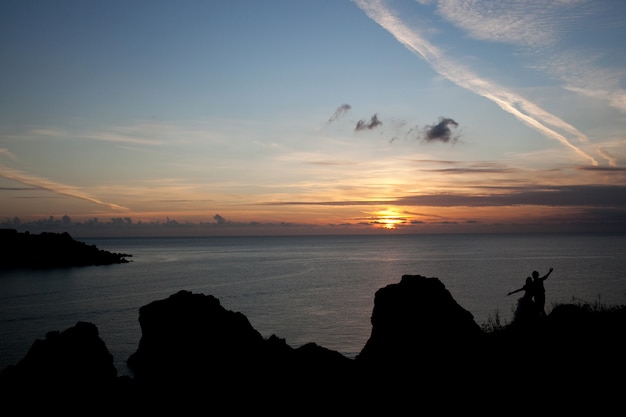 La sposa e lo sposo allargano le loro mani mentre guardano il tramonto