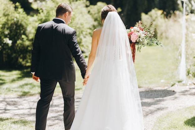 La sposa e lo sposo si tengono per mano davanti all&#39;arco