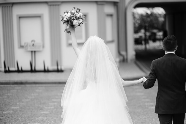 La sposa e lo sposo tengono insieme le loro mani mentre camminano intorno