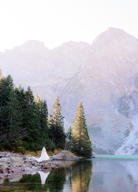 La sposa emozionante sta stando circondata con la bellezza del lago e delle montagne dell'altopiano