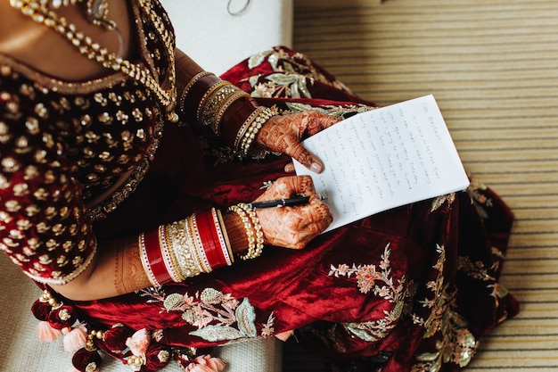 La sposa in abiti tradizionali indiani sta scrivendo i suoi voti sulla carta