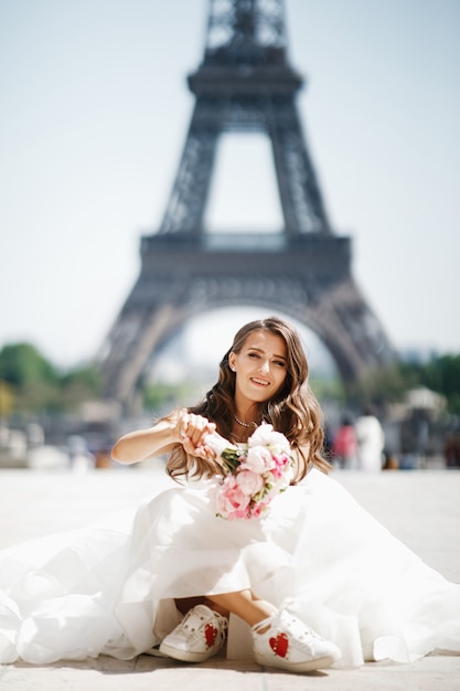 La sposa si siede in risatine prima della torre Eiffel a Parigi