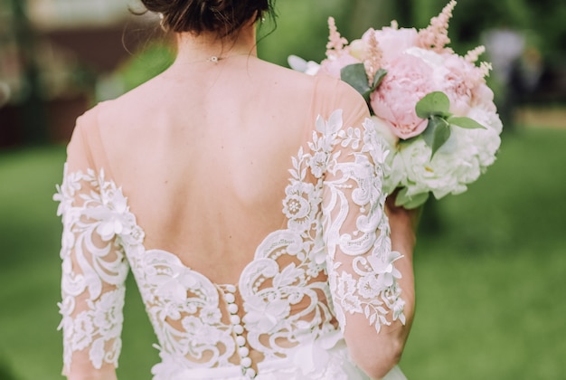 la sposa sta dietro con un mazzo di fiori