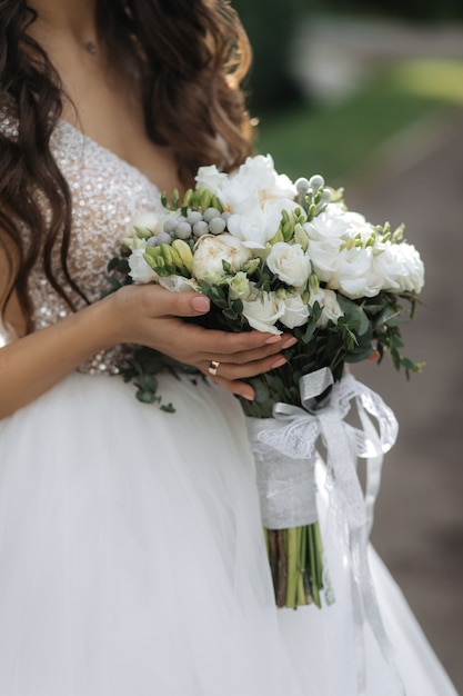 La sposa tiene il bellissimo bouquet da sposa con rose bianche e peonie