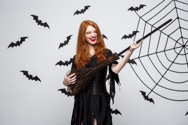 La strega elegante felice di concetto di Halloween si diverte a giocare con la festa di halloween del manico di scopa