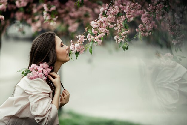 La tendenza della ragazza annusa un sakura nel parco