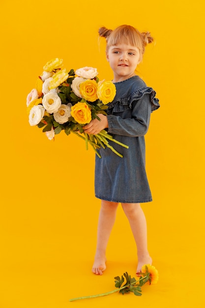 La tenuta innocente del bambino fiorisce la foto a figura intera