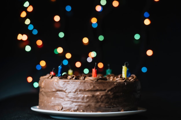 La torta di cioccolato contro il bokeh di scintillio illumina il contesto nero