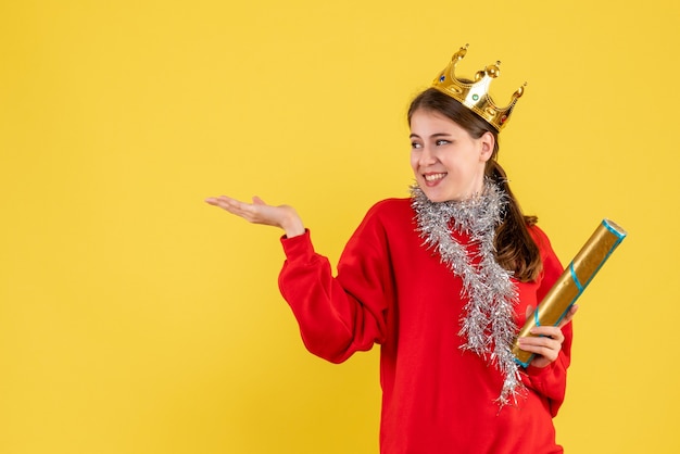 La vista frontale ha rallegrato la ragazza con il maglione rosso che tiene il popper del partito che indica con il dito verso l'alto