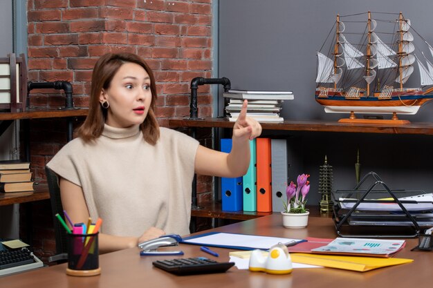 La vista frontale ha sorpreso la bella donna che lavora in ufficio