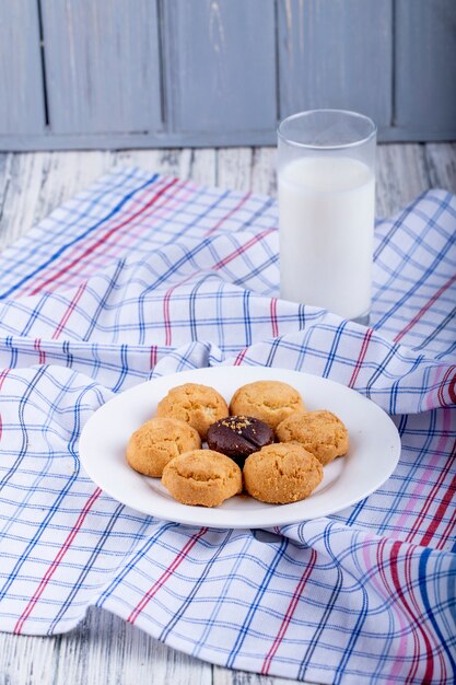 La vista laterale dei biscotti su un piatto bianco è servito con un bicchiere di latte