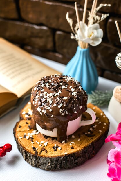 La vista laterale del dolce di budino al cioccolato con cioccolato spruzza in una tazza su un bordo di legno