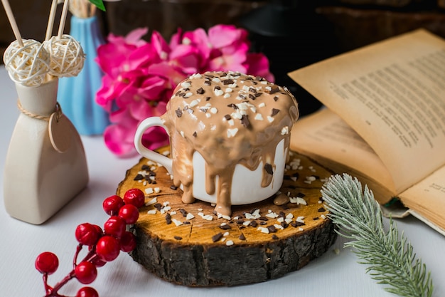 La vista laterale del dolce di budino al cioccolato con cioccolato spruzza su un bordo di legno