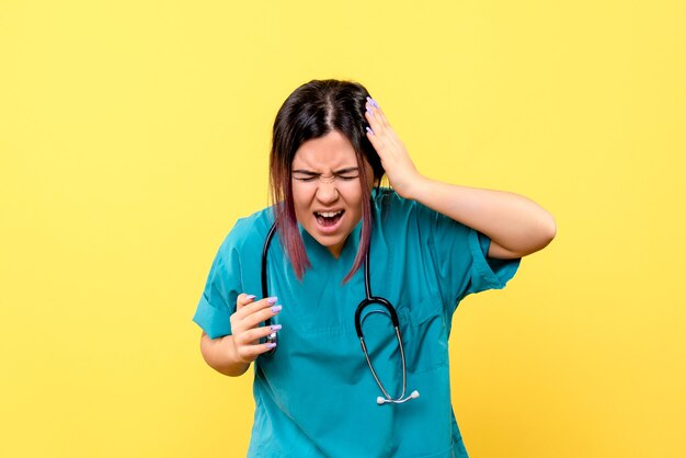 La vista laterale del medico in uniforme medica blu ha un mal di testa