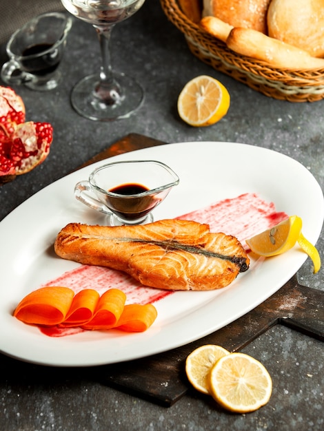 La vista laterale del salmone al forno è servito con salsa e limone del melograno di narsharab sul piatto bianco