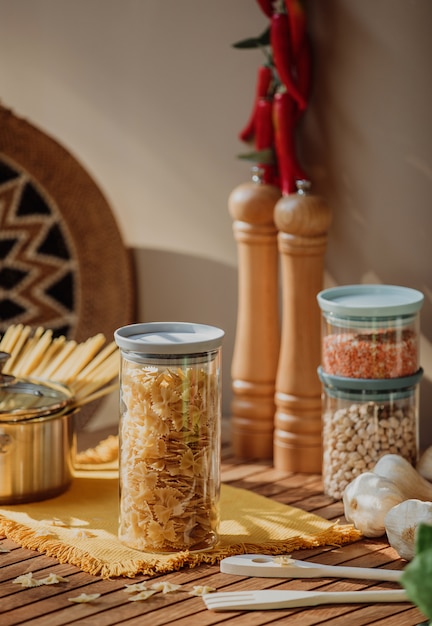 La vista laterale di un barattolo di vetro ha riempito di pasta cruda del farfalle su una tavola di legno