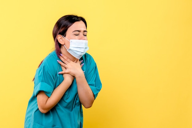 La vista laterale di un medico in maschera parla dei sintomi del covid