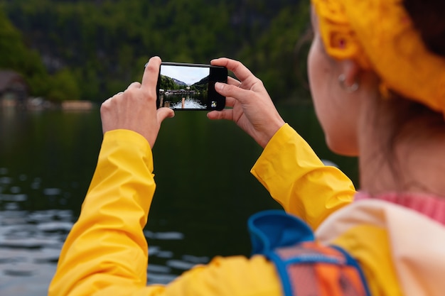 La vista posteriore del modello femminile irriconoscibile fa la foto sullo smartphone