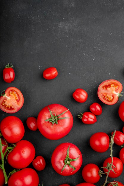 La vista superiore dei pomodori rossi maturi freschi ha sparso su fondo nero con lo spazio della copia