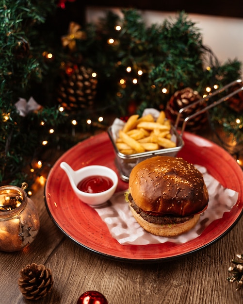 La vista superiore dell'hamburger di manzo è servito con le decorazioni di natale dell'orecchio del ketchup delle patate fritte