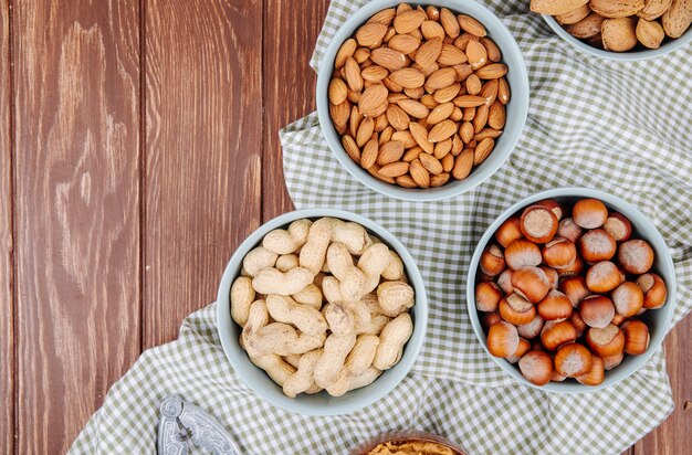 La vista superiore delle ciotole ha riempito di nocciole miste miste mandorle e noci su fondo di legno con lo spazio della copia