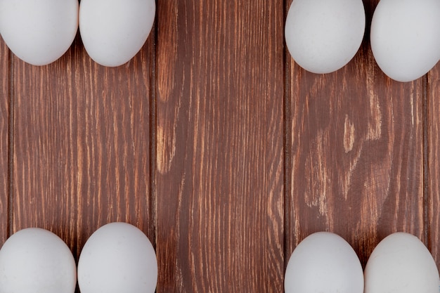 La vista superiore delle uova fresche bianche del pollo ha sistemato nei lati differenti su un fondo di legno con lo spazio della copia