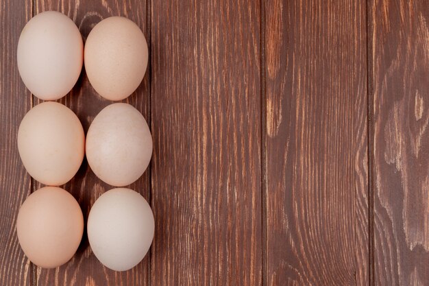 La vista superiore delle uova fresche del pollo ha sistemato su un fondo di legno con lo spazio della copia