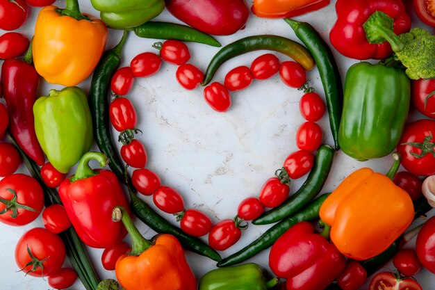 La vista superiore delle verdure mature fresche ha sistemato in un peperone dolce verde del peperoncino di forma del cuore su fondo di marmo