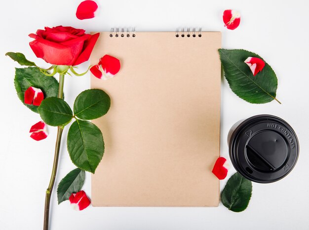 La vista superiore di colore rosso è aumentato con uno sketchbook e una tazza di caffè su fondo bianco
