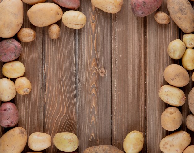 La vista superiore di intere patate ha messo nella forma circolare su fondo di legno con lo spazio della copia