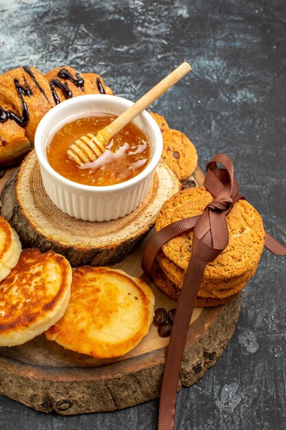 La vista verticale della colazione deliziosa con i pancake del croissant ha impilato il miele dei biscotti sulla tavola scura