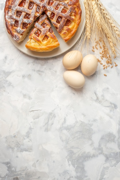 La vista verticale della deliziosa torta di marmellata su un piatto bianco uova picchi sul tavolo bianco