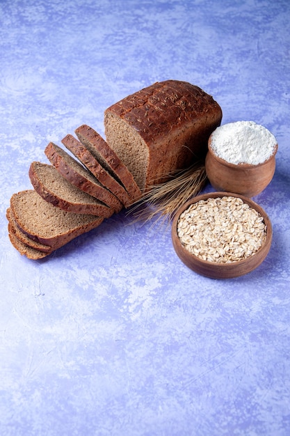 La vista verticale della farina d'avena della farina delle fette del pane nero sul fondo del modello blu ghiaccio chiaro con spazio libero