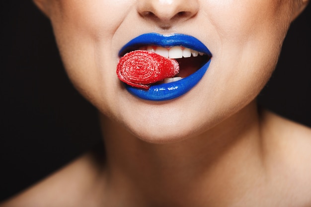 labbra colorate allegre che tengono le caramelle con i denti.