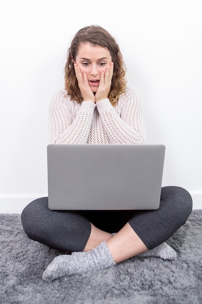 Lady preoccupata che lavora al computer portatile sul pavimento