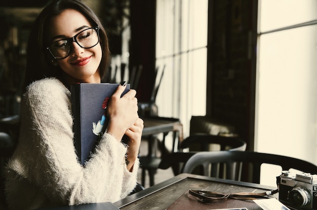 Lady tiene tenera vecchia fotoalbums seduto nel caffè