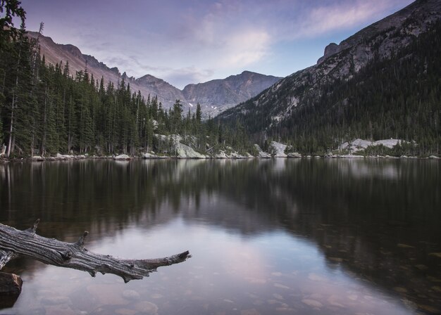 Lago calmo con alberi e montagne