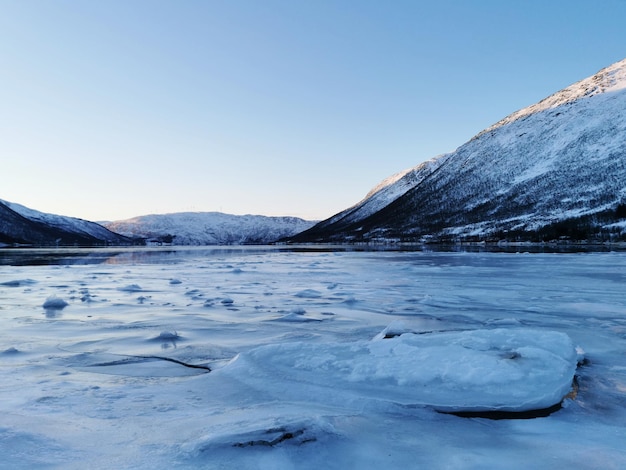 Lago ghiacciato da colline innevate a Kattfjorden, Norvegia catturato durante il giorno