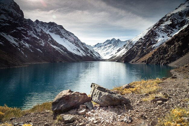 Lago Laguna del Inca circondato da alte montagne coperte di neve in Cile