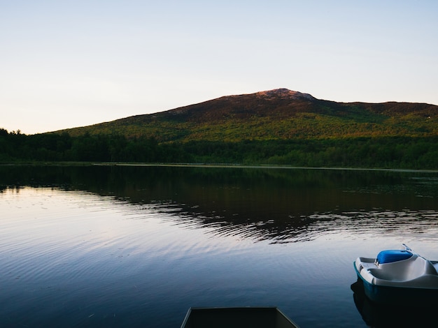 Lago tranquillo ai piedi di una montagna contro un cielo luminoso