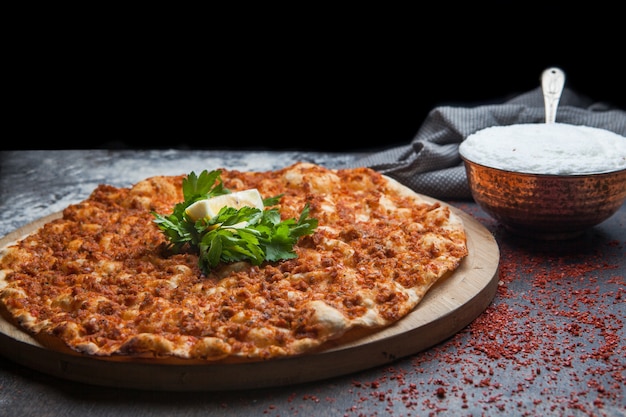 Lahmacun di vista laterale con prezzemolo e limone e ayran e straccio in vassoio di legno dell'alimento