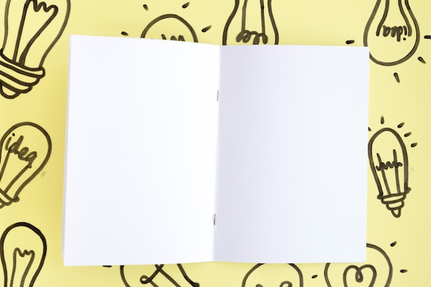 Lampadina disegnata bianca vuota della pagina bianca a disposizione sopra i precedenti gialli