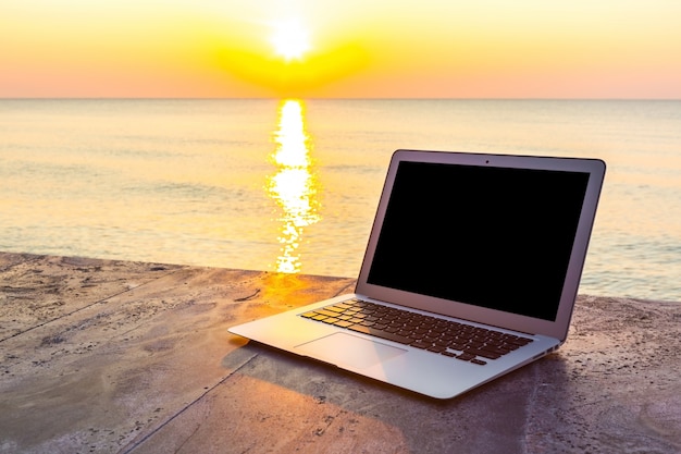 Laptop sulla superficie di pietra e lo sfondo del mare