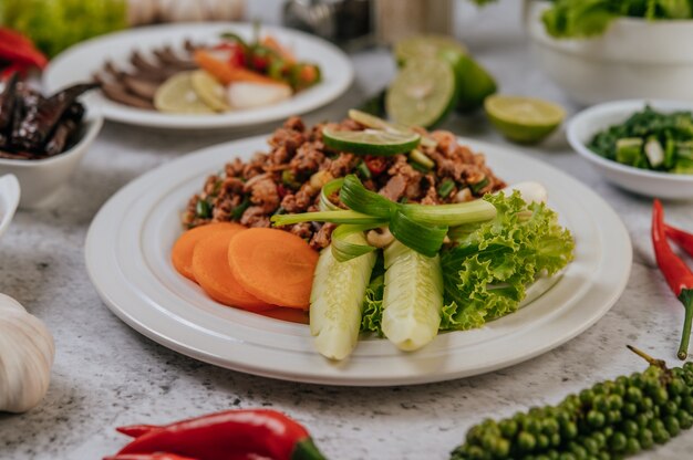 Larb di maiale con carota, cetriolo, lime, cipollotto, peperoncino, pepe appena macinato e lattuga.