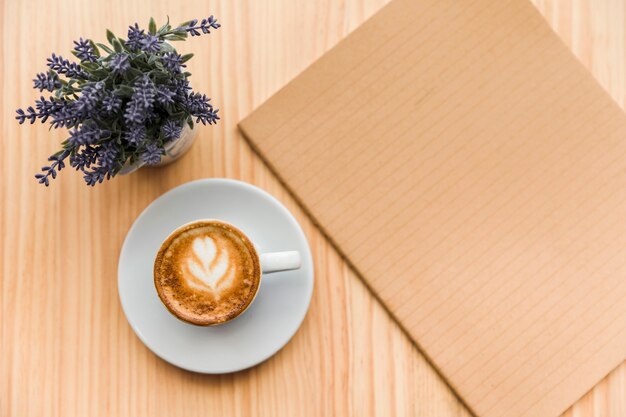 Latte del caffè con il fiore e il taccuino della lavanda su fondo di legno