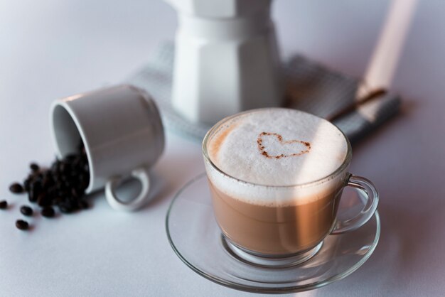 Latte della tazza di caffè del primo piano con il bollitore